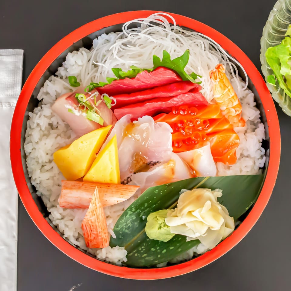 A vibrant Koiso chirashi bowl with various sashimi, tamago, and crab sticks over rice.